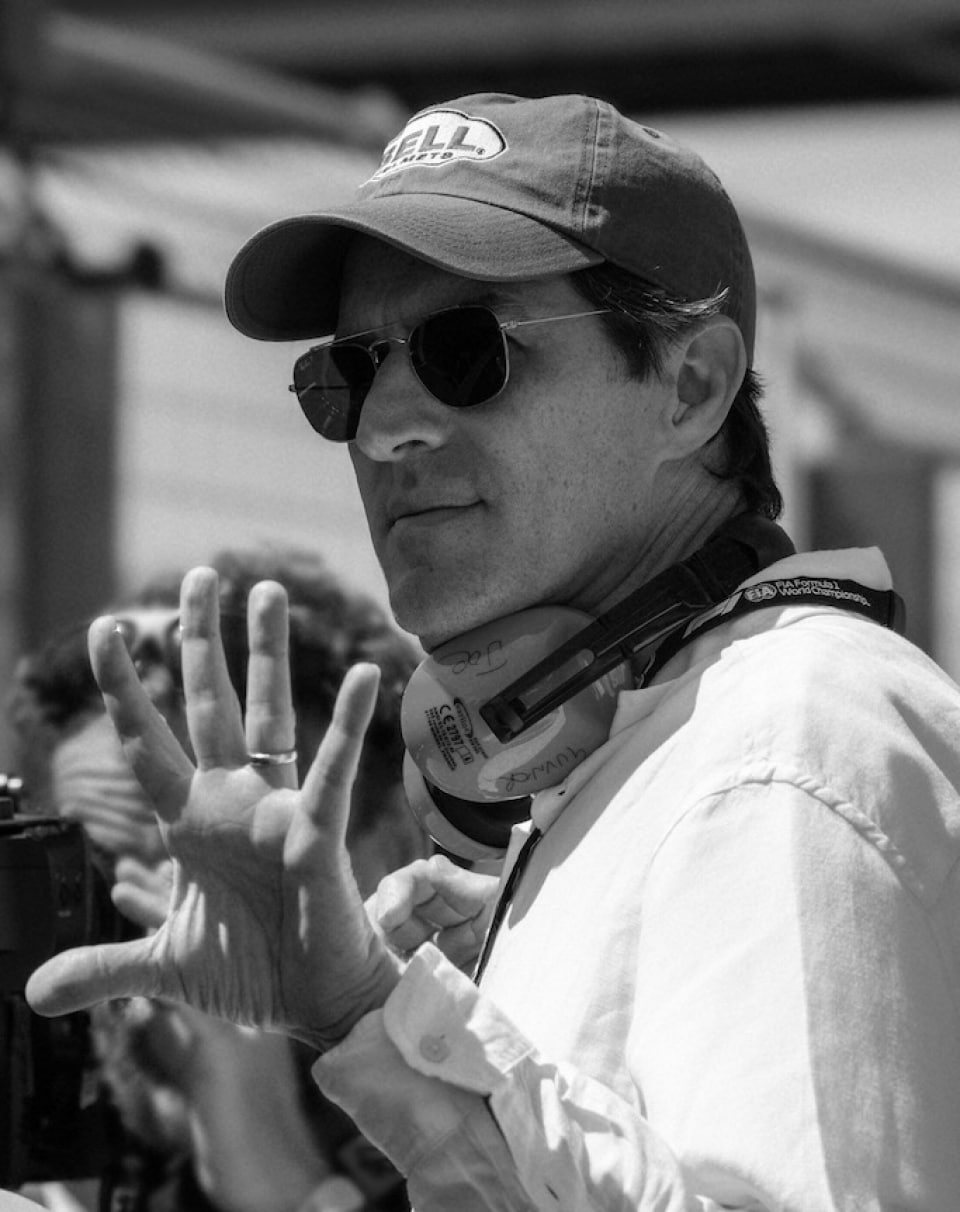 Film director Joseph Kosinski standing next to a camera during a film shoot and directing his team.