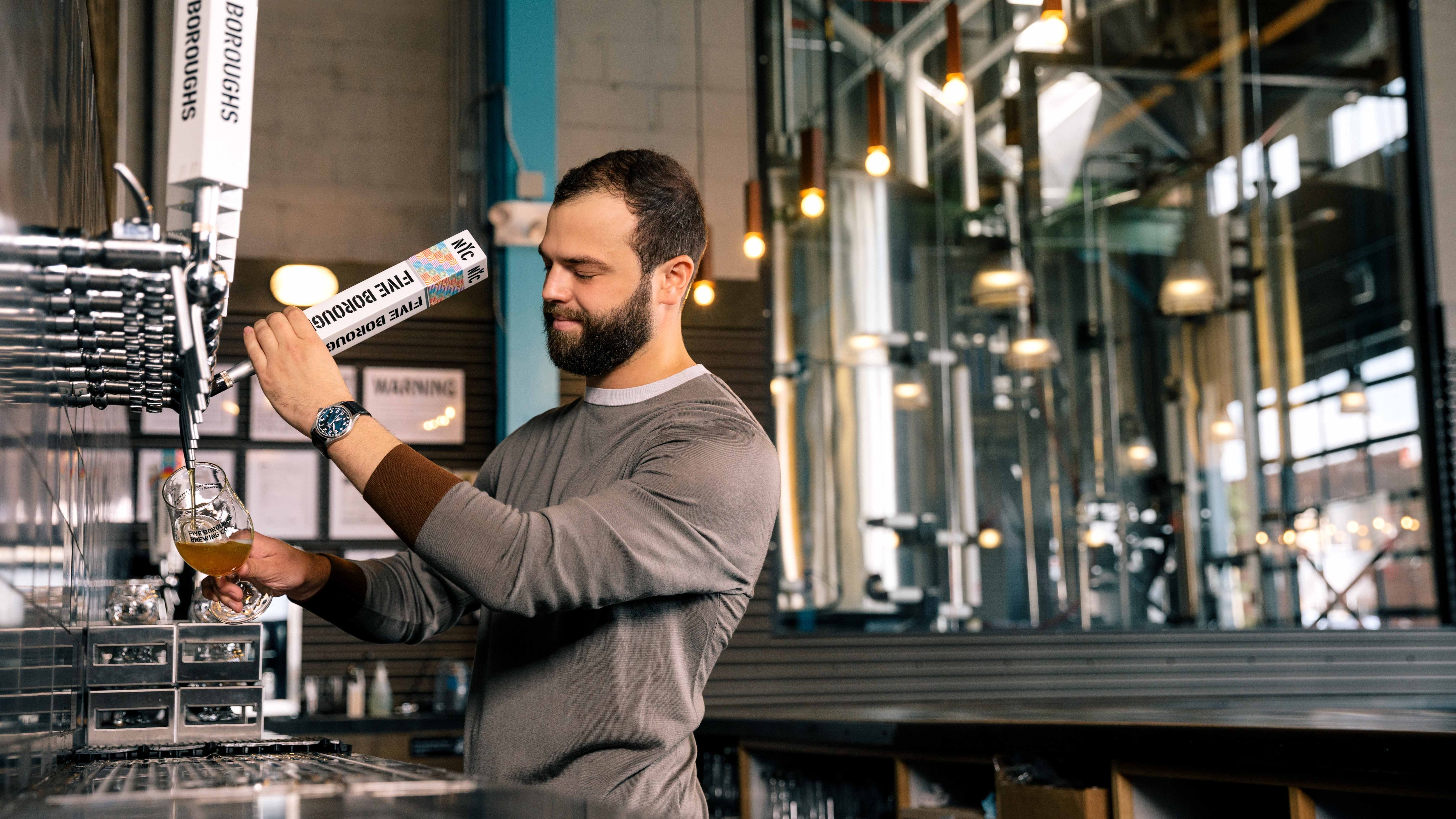 Blake Tomnitz pouring a drink from a tap behind a bar.